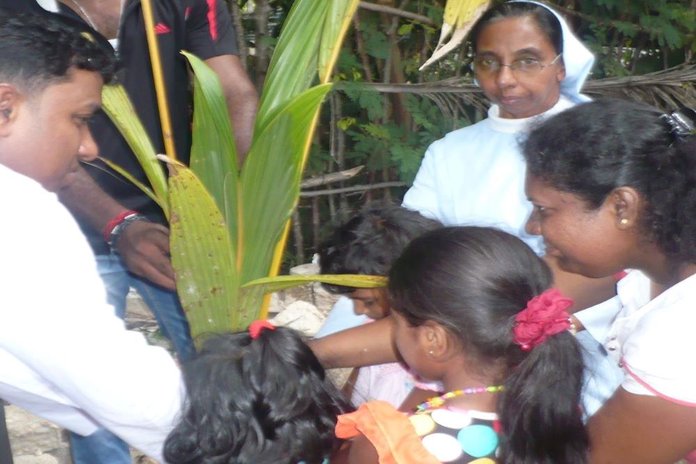 Sinhala guests of a Tamil family plant a coconut tree in memory of their live-in experience as Salvatorian Sr. Dulcie Peiris looks on. (Courtesy of Dulcie Peiris)