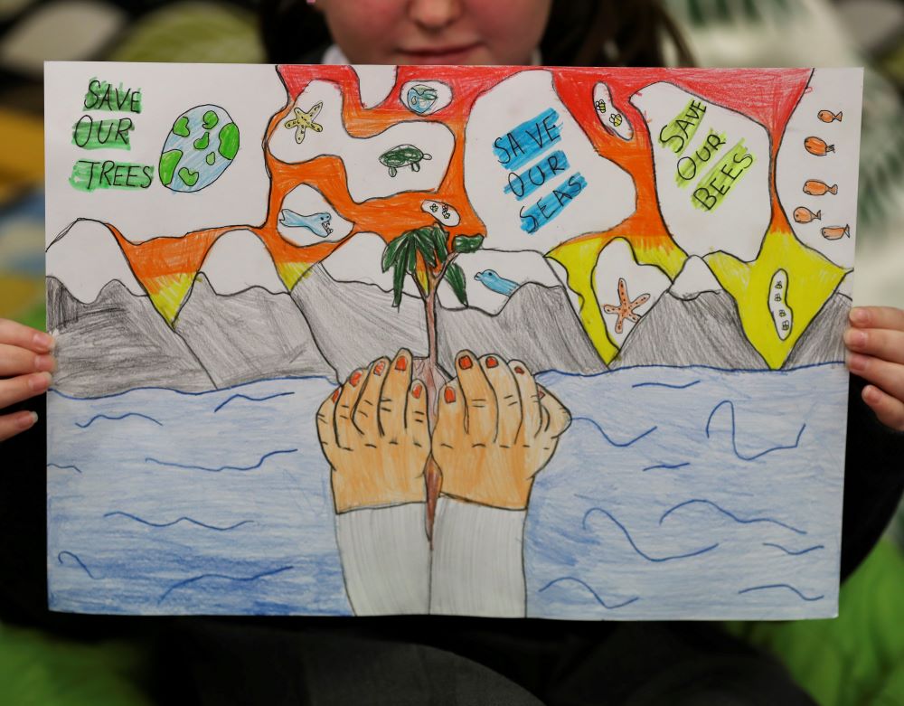 A student holds a poster at St. Conval's Primary School in Glasgow, Scotland, while learning about climate change ahead of COP26, the U.N. Climate Change Conference, which starts Oct. 31. (CNS/Reuters/Russell Cheyne)