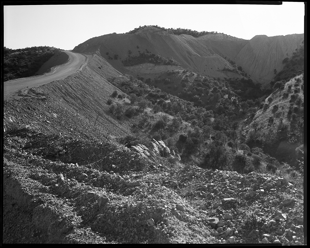 Along the rolling hills and deep arroyo near the edge of the Pajarito Mountains that straddle the U.S.-Mexico border near Nogales, travelers can see a gravel road zigzagging up the disfigured faces of mountainsides, probably blasted by explosives. Where d