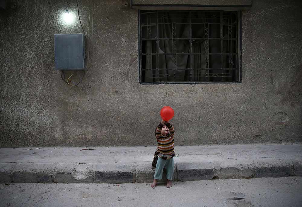 A child plays with a balloon Nov. 13, 2016, in Douma, Syria. In previous years, sanctions by the United States denied industrial parts to Syria and crippled its airline industry. (CNS/Reuters/Bassam Khabieh)