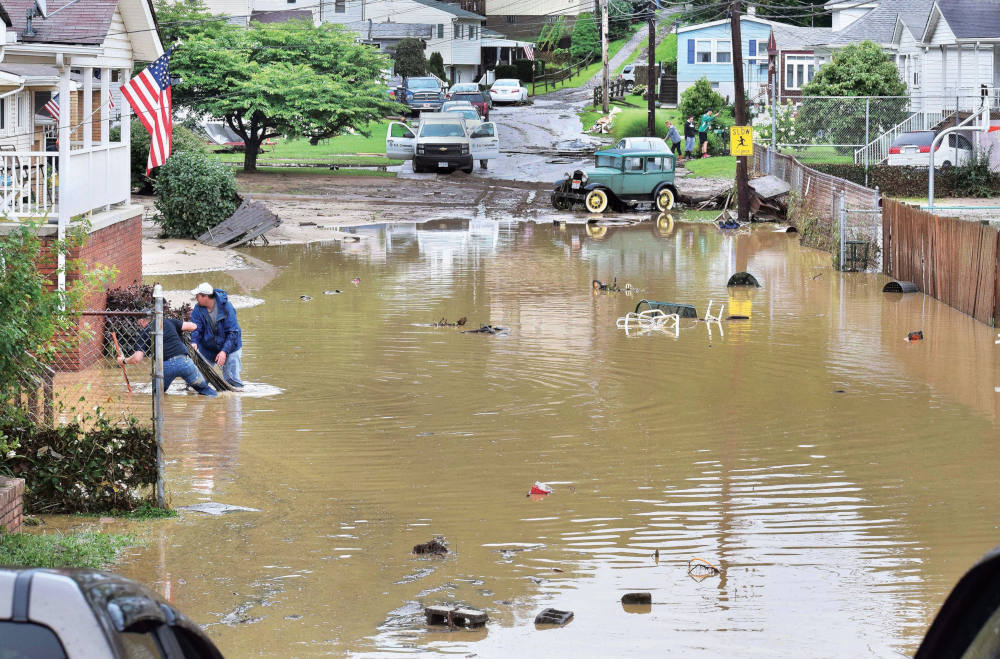 Men clear debris after flooding July 29, 2017, in McMechen, W.Va. As many as 400 homes and businesses in Marshall County sustained water damage. The worst of it was in McMechen, where runoff flowed down the hillside and flooded the town. (CNS photo)