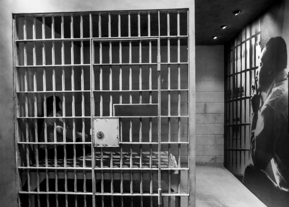 A visitor sits in a replica of a jail cell next to a portrait of the Rev. Martin Luther King Jr., in 2015 at the National Civil Rights Museum in Memphis, Tennessee. (CNS/EPA/Tannen Maury)