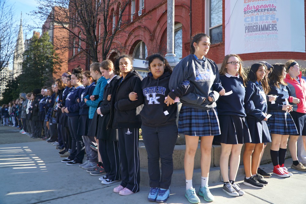 Presentation Academy students stand arm in arm on the sidewalk in downtown Louisville, Kentucky, after walking out of class March 14, 2018, to call attention to gun violence. (CNS/The Record/Marnie McAllister)