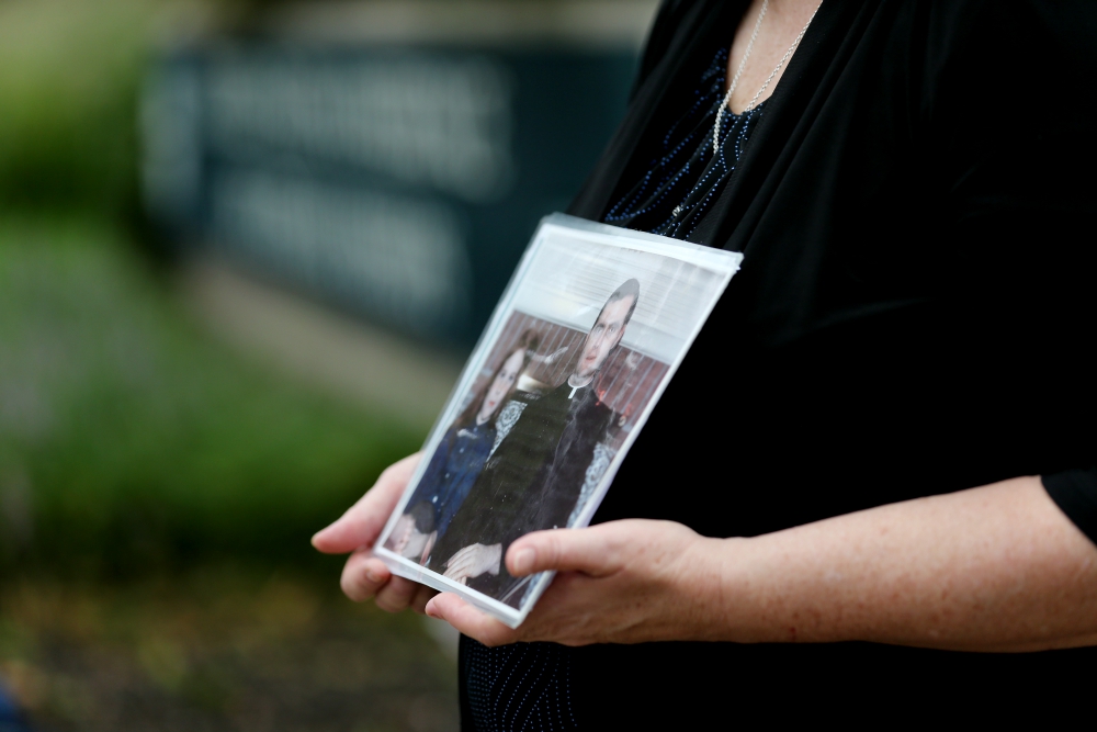 Becky Ianni holds a photo of herself as a child with a priest Aug. 21 outside the headquarters of U.S. Conference of Catholic Bishops in Washington. Ianni says she was abused by the priest in the photo. (CNS/Bob Roller)