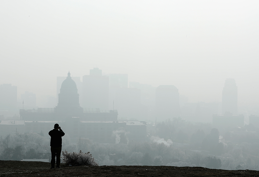 A man stops to take a picture of the Utah State Capitol and buildings that are shrouded in smog in downtown Salt Lake City Dec. 12, 2017. (CNS/Reuters/George Frey)