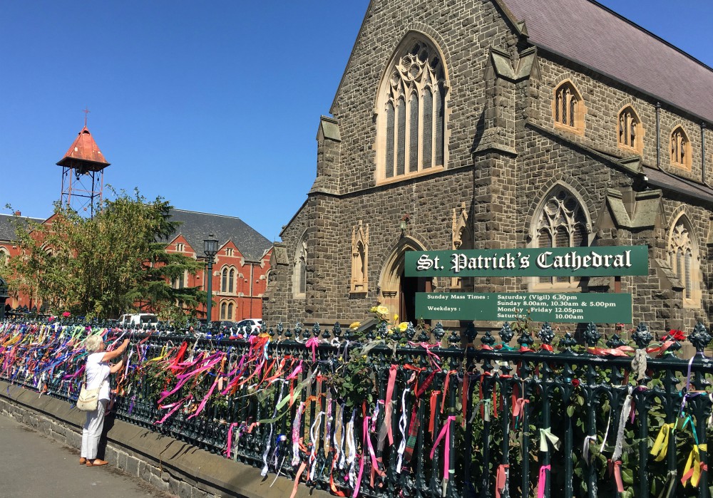 A woman puts a ribbon on the fence of St. Patrick's Cathedral in Ballarat, Australia, in February 2019. The ribbons raise awareness and show support for victims of abuse. (CNS/Reuters/Jonathan Barrett)