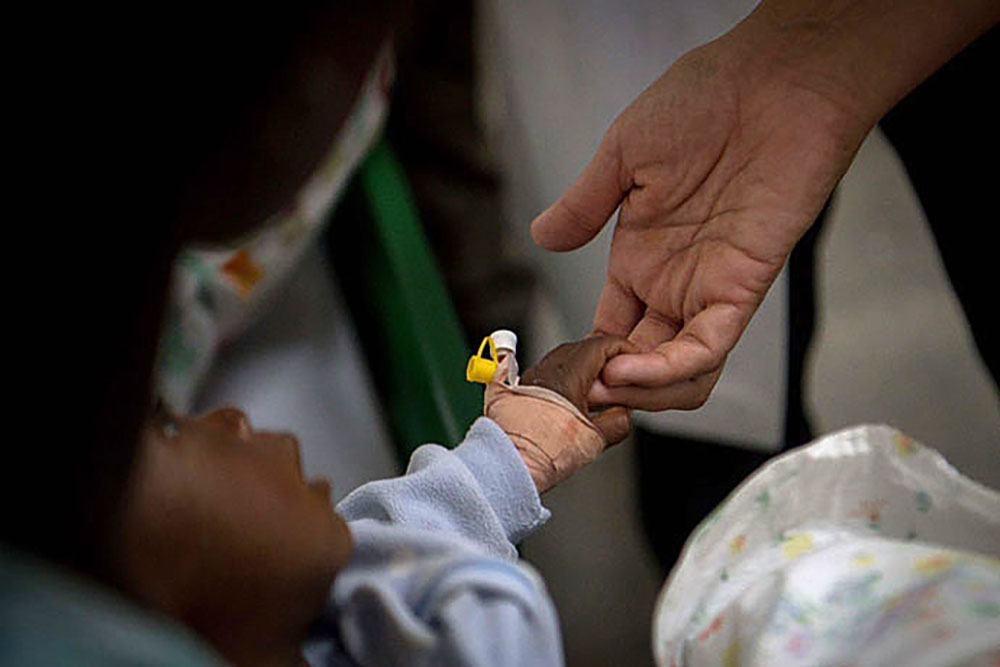 An Ursuline sister holds the hand of an infant patient in a cholera clinic in Verrettes, Haiti, in 2017. (CNS/Journey Press/Bryan Woolston)