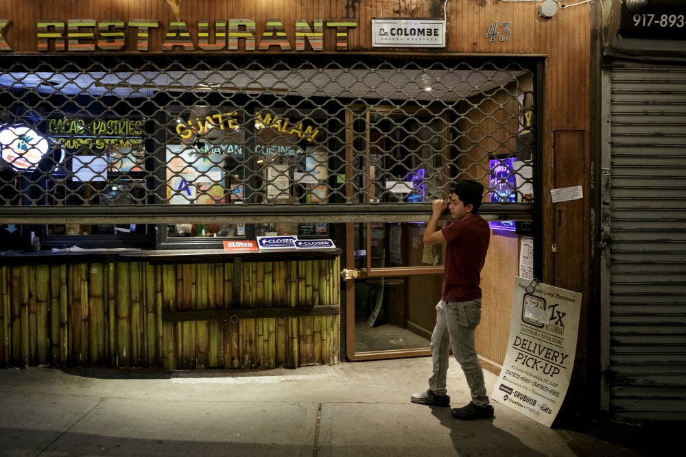 An employee closes the gate of a Latino restaurant in New York City April 2 during the coronavirus pandemic. (CNS/Reuters/Anna Watts)