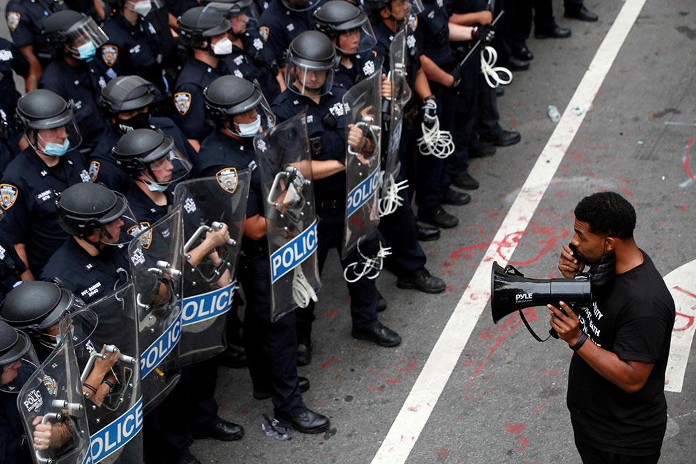A demonstrator with Black Lives Matter stands in front of police officers in New York City inside of an area called the "City Hall Autonomous Zone" July 1. (CNS/Reuters/Andrew Kelly) A demonstrator with Black Lives Matter stands in front of police officers in New York City inside of an area called the "City Hall Autonomous Zone" July 1. (CNS/Reuters/Andrew Kelly)