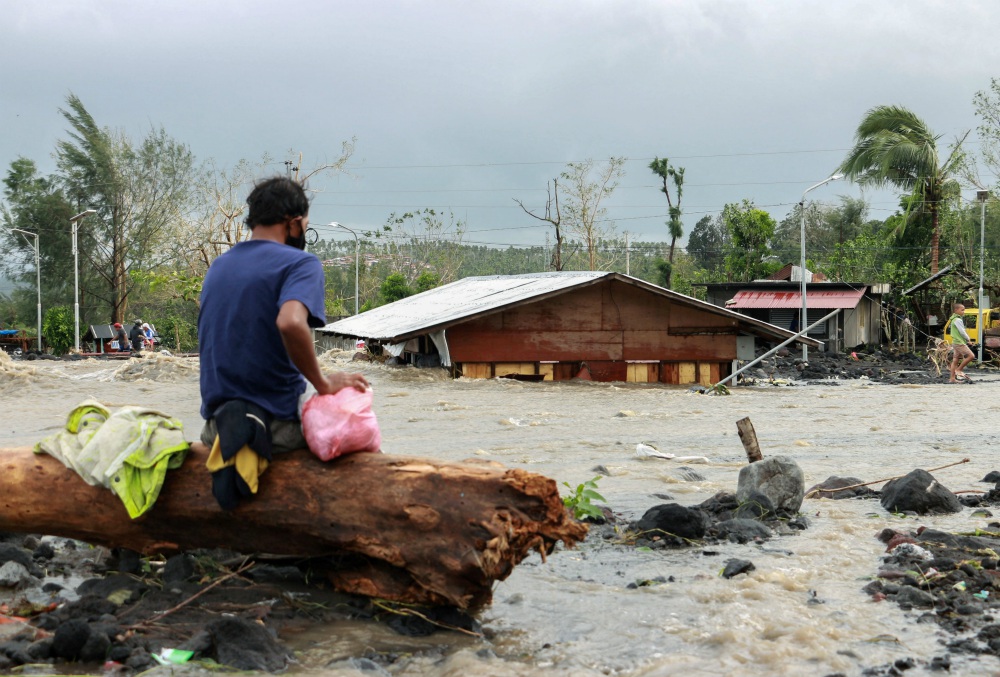 A man looks at his house buried under the pile of rubble and sand in Daraga, Philippines, Nov. 1, following flash floods brought by Super Typhoon Goni, also known as Rolly. The storm left at least 10 people dead and three missing. (CNS/Reuters)