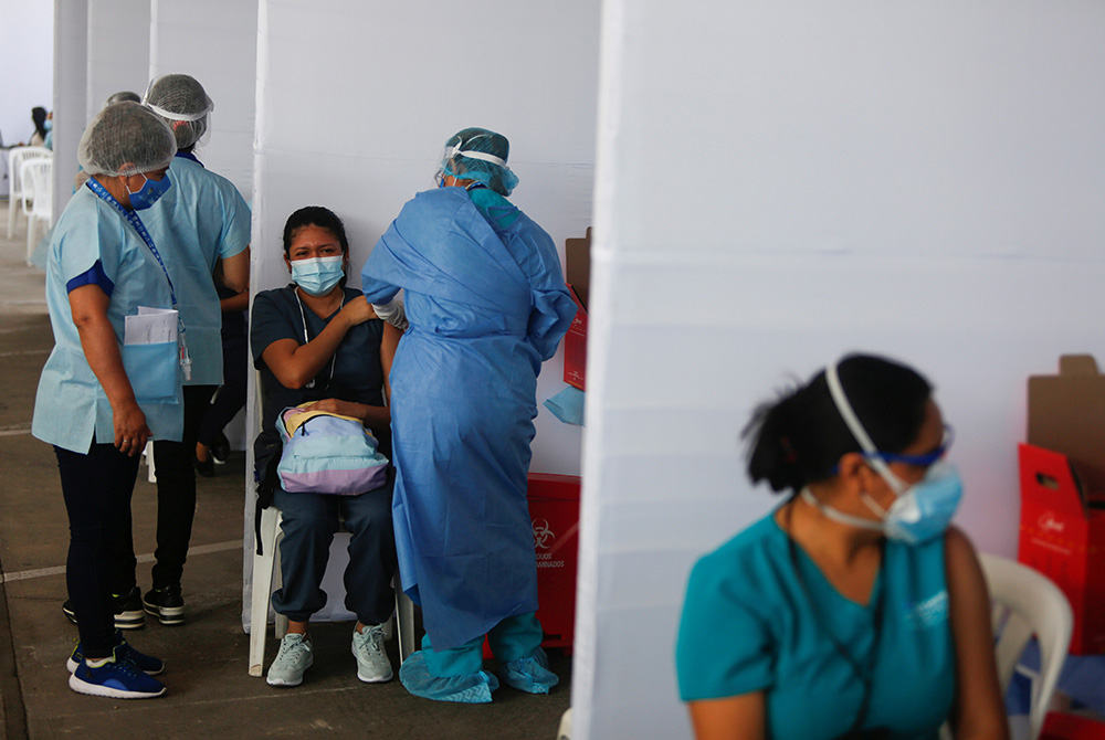 A health care worker receives a dose of Sinopharm's COVID-19 vaccine Feb. 9 in Lima, Peru. Peru's bishops denounced the giving of vaccines to VIPs instead of essential workers after the vaccine became available. (CNS/Reuters/Sebastian Castaneda)