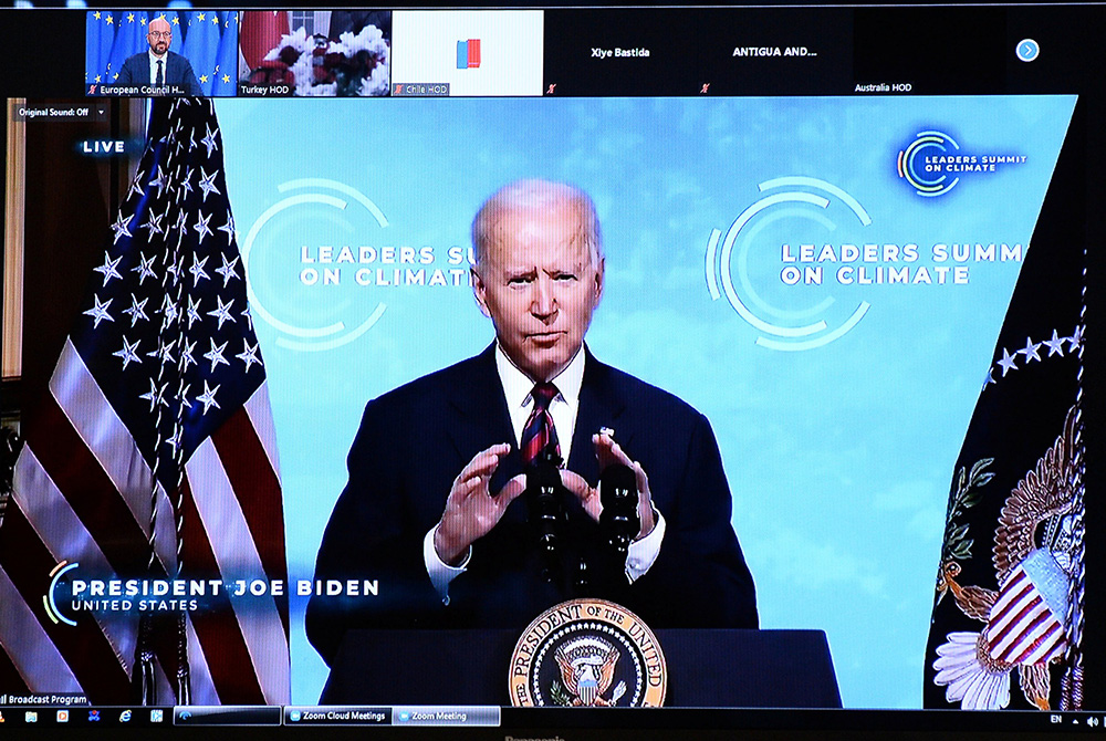 President Joe Biden is seen on a screen in Brussels, Belgium, April 22, 2021, as European Council President Charles Michel attends a virtual global climate summit. Biden committed the United States to cut greenhouse emissions in half by 2030. (CNS/Johanna President Joe Biden is seen on a screen in Brussels, Belgium, April 22, 2021, as European Council President Charles Michel attends a virtual global climate summit. Biden committed the United States to cut greenhouse emissions in half by 2030. (CNS/Johanna