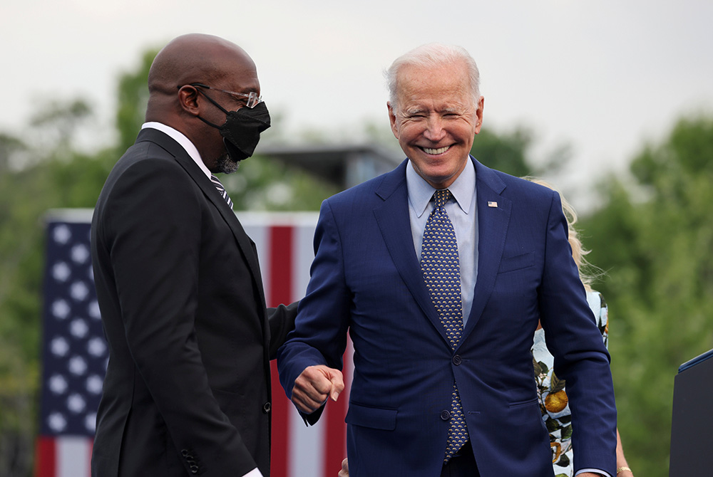President Joe Biden smiles next to Sen. Raphael Warnock, D-Georgia, at the Infinite Energy Center April 29 in Duluth, Georgia, during the Democratic National Committee's "Back on Track" drive-in car rally to celebrate the president's 100th day in office. President Joe Biden smiles next to Sen. Raphael Warnock, D-Georgia, at the Infinite Energy Center April 29 in Duluth, Georgia, during the Democratic National Committee's "Back on Track" drive-in car rally to celebrate the president's 100th day in office.