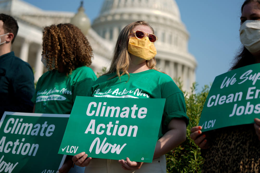 People hold League of Conservation Voters signs during a news conference urging action on climate change outside the U.S. Capitol in Washington July 28, 2021. (CNS photo/Elizabeth Frantz, Reuters)