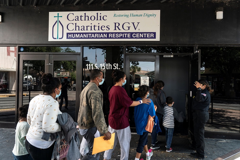 Migrants seeking asylum in the United States walk into a temporary humanitarian respite center run by Catholic Charities of the Rio Grande Valley in McAllen, Texas, on April 8.