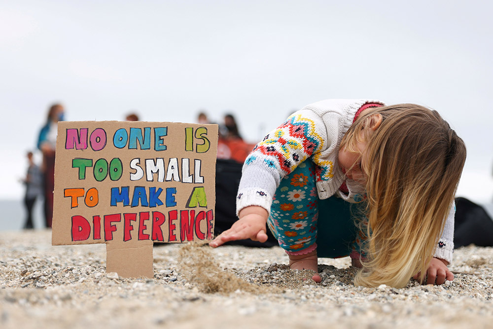 A girl in Falmouth, Britain, plays with sand during a climate protest June 11. (CNS/Reuters/Tom Nicholson)