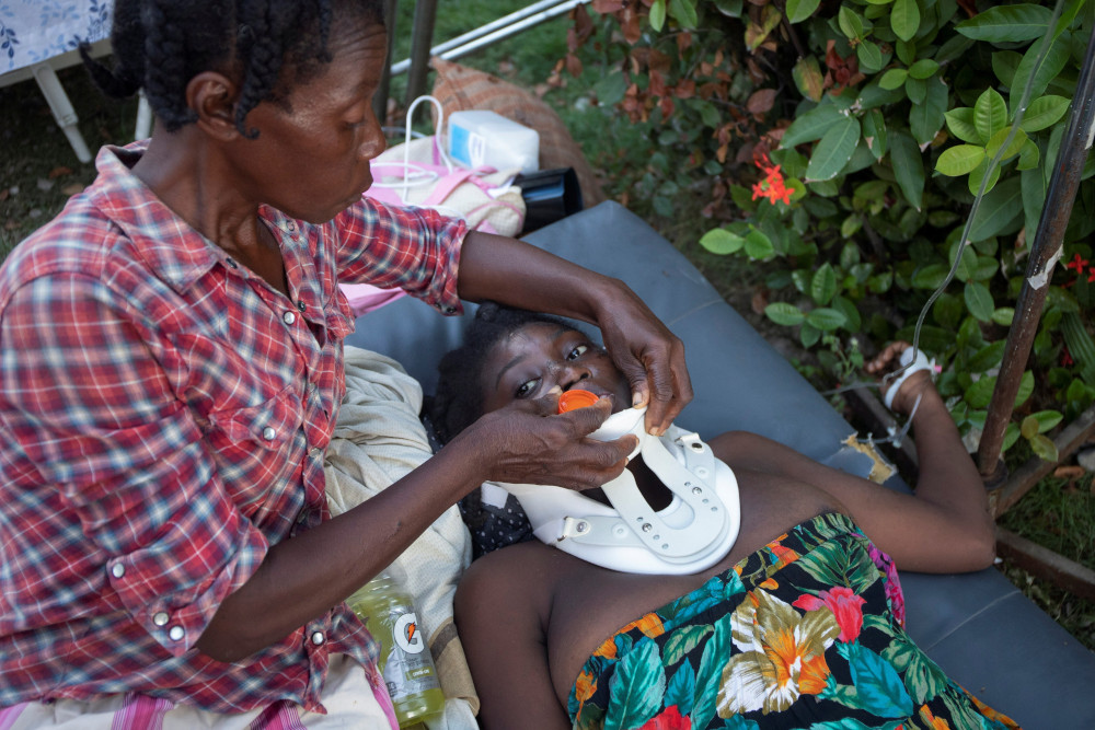 An injured woman is assisted Aug. 15 in Les Cayes, Haiti, following magnitude 7.2 earthquake the previous day. (CNS/Reuters/Estailove St-Val)