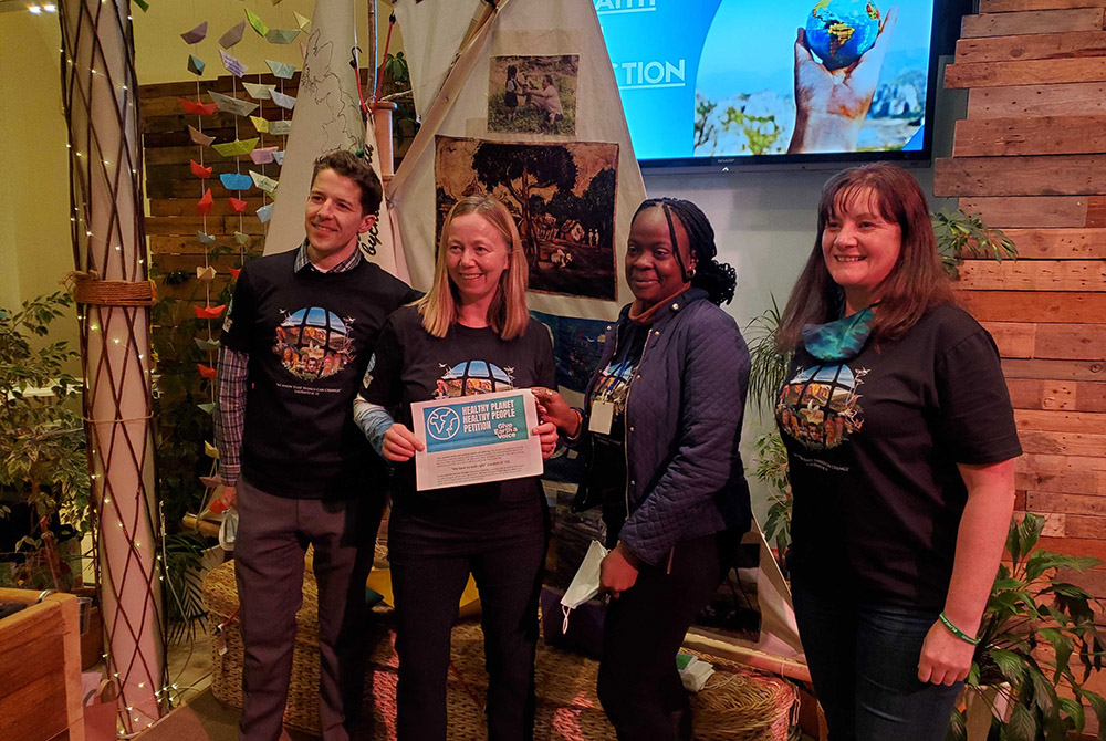 Members of the Laudato Si' Movement present a copy of the Healthy Planet, Healthy People petition, which drew more than 120,000 signatures from Catholics, during an event at St. George's Tron Church Nov. 2 in central Glasgow, Scotland. (EarthBeat photo)