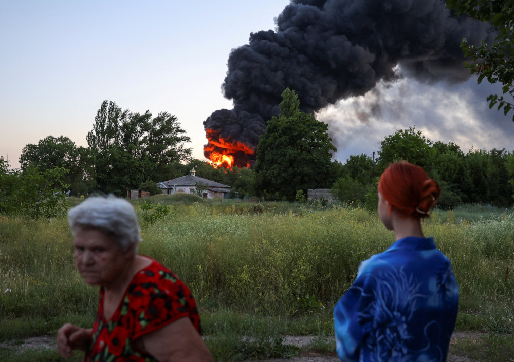 Local residents in Donetsk, Ukraine, look on as smoke rises after shelling from Russia July 7, 2022. (CNS photo/Alexander Ermochenko, Reuters)