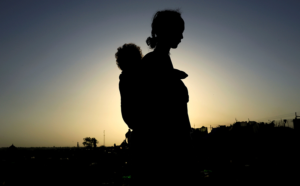 An Ethiopian woman who fled the ongoing fighting in Tigray region, carries her child near the Setit river on the Sudan-Ethiopia border Nov. 22, 2020. (CNS/Reuters/Mohamed Nureldin Abdallah)