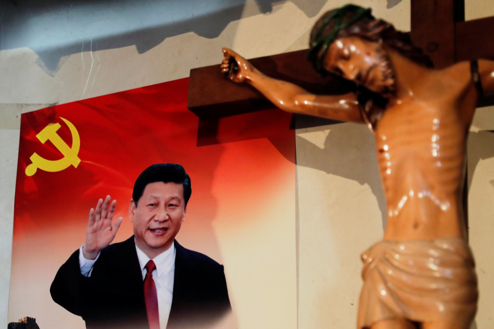 A poster of Chinese President Xi Jinping hangs next to a crucifix on the wall of the house of a Tibetan Catholic