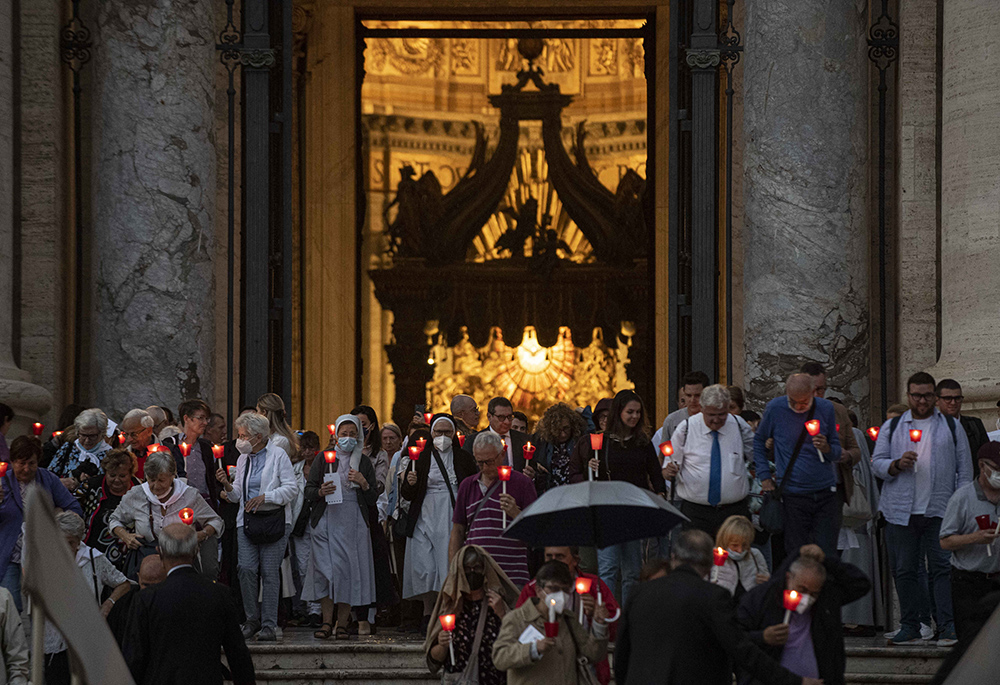 People holding lighted candles leave St. Peter's Basilica after Pope Francis celebrated Mass Oct. 11 to mark the 60th anniversary of the opening of the Second Vatican Council. (CNS/Vatican Media)