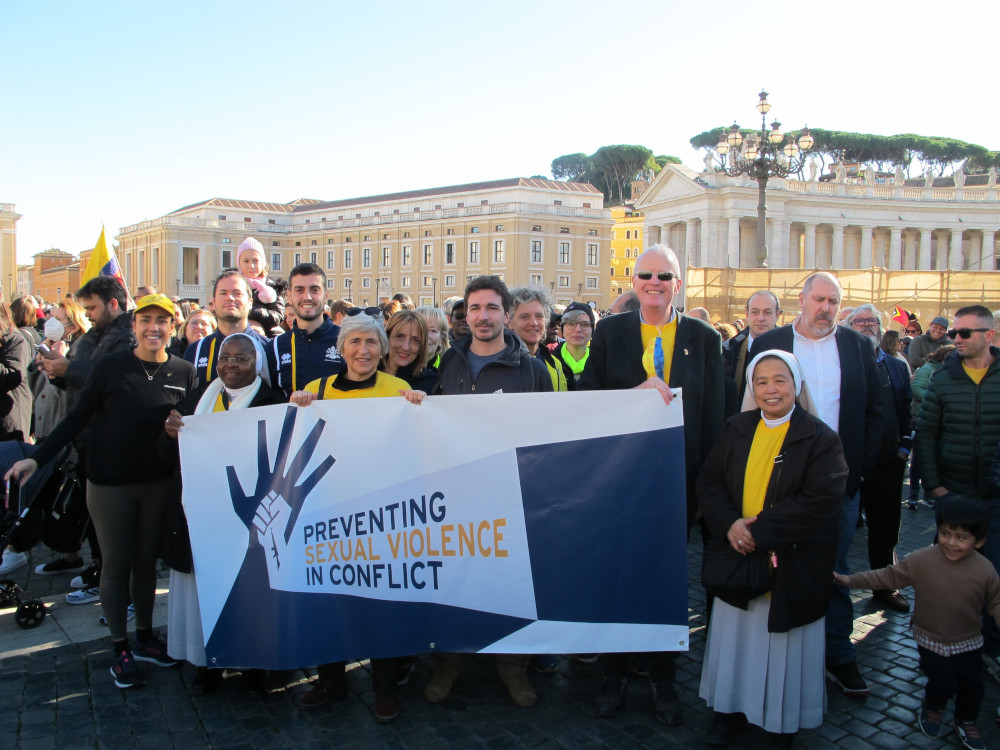 Women religious and men hold a banner that says "Preventing sexual violence in conflict"