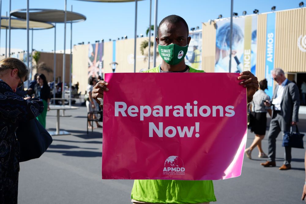 An activist carries a placard as he demonstrates at the central area of the conference center in Sharm el-Sheikh, Egypt, Nov. 9, 2022. (Doreen Ajiambo)