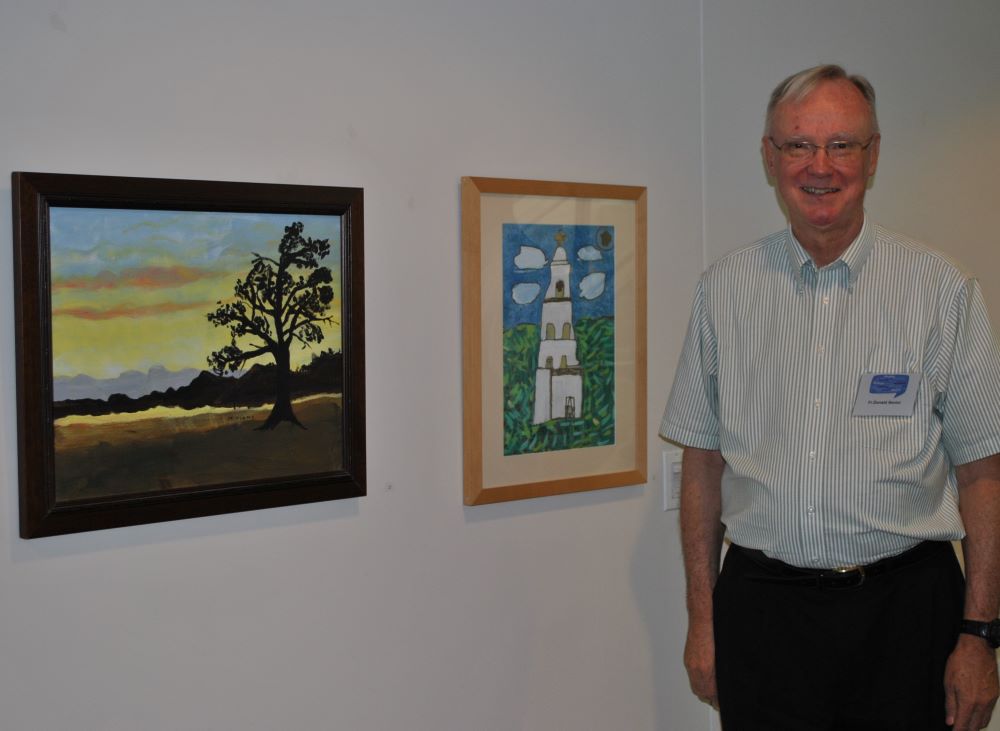 Passionist Fr. Donald Senior, then president of Catholic Theological Union, stands next to his sister Miriam's paintings during the Summer Institute on Theology and Disability at CTU in Chicago, July 16-20, 2012. He died Nov. 8 at age 82. (NCR photo/Teresa Malcolm)