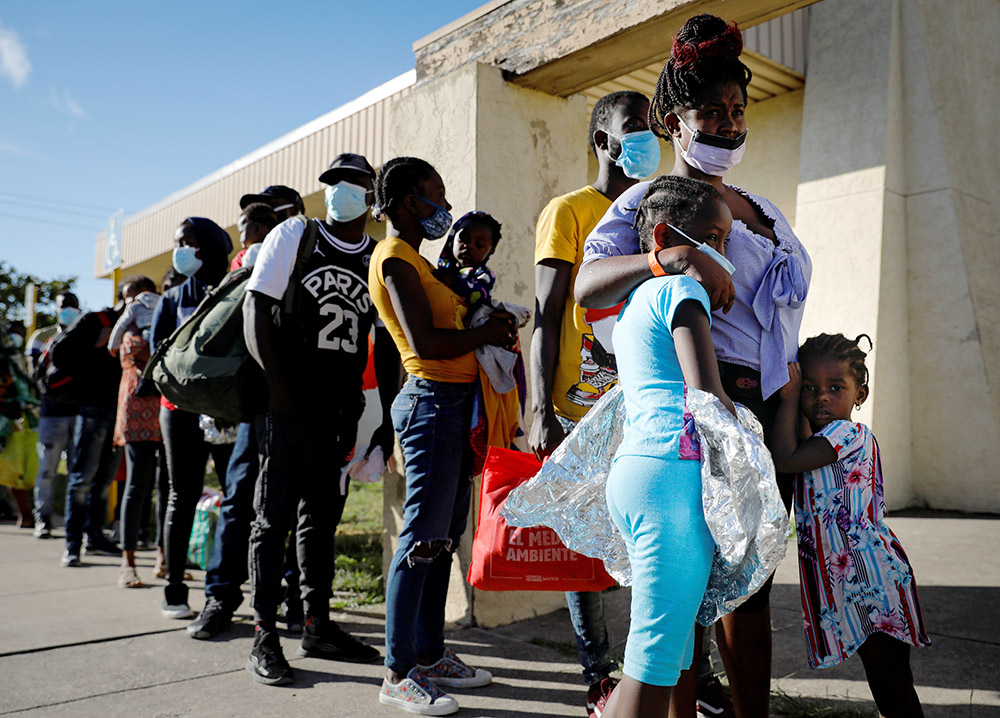 Migrants released from U.S. Customs and Border Protection in Del Rio, Texas, wait in line to board a bus to Houston Sept. 24, 2021. (CNS/Reuters/Marco Bello)