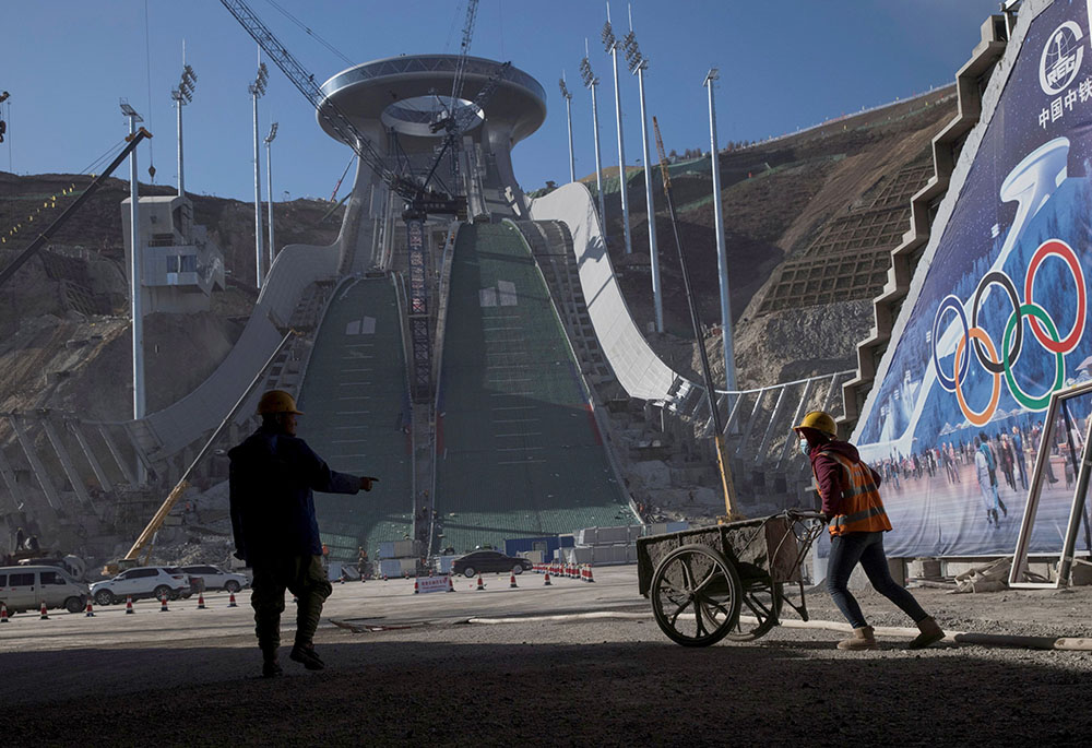 Workers are silhouetted Oct. 29, 2020, at the Thaiwoo ski resort near skiing venues of the 2022 Winter Olympics in Chongli, a popular ski resort town in China. The venue is one of many in the Beijing area that will host the Olympic Winter Games Feb. 4-20.