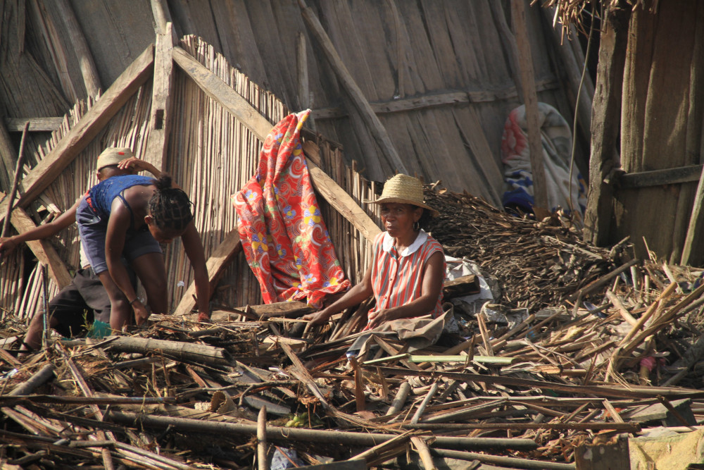 A Malagasy family is pictured outside their destroyed home Feb. 8, 2022, in Mananjary, Madagascar, in the aftermath of Cyclone Batsirai. (CNS/courtesy CRS)