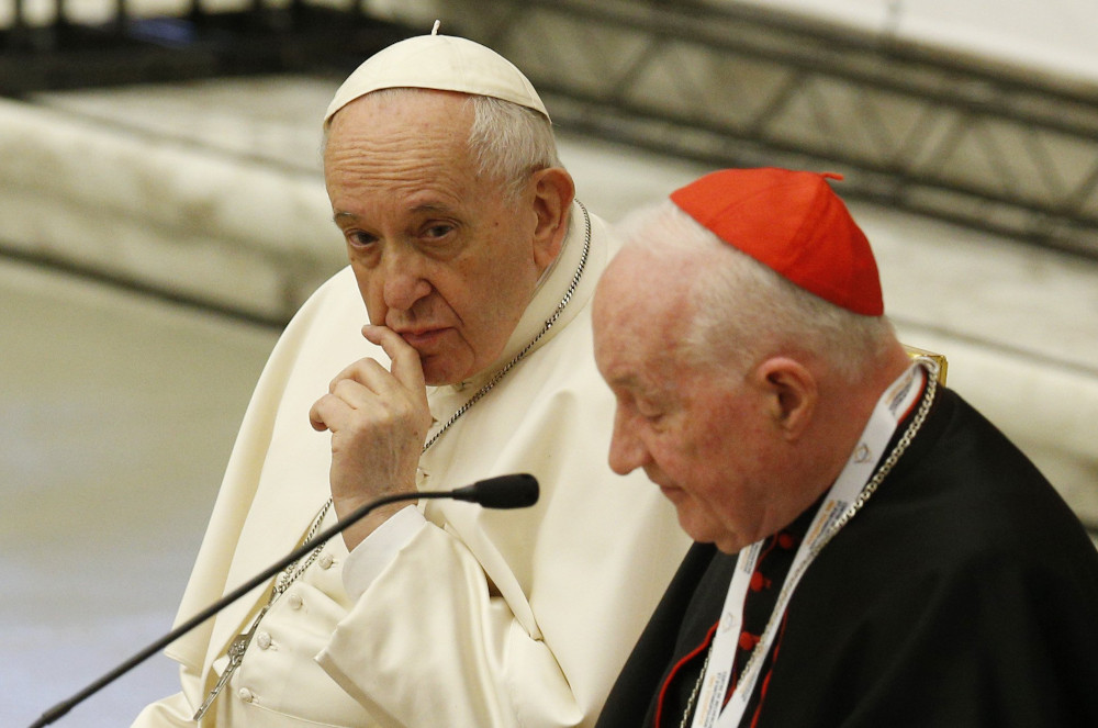 Pope Francis looks on as Cardinal Marc Ouellet, prefect of the Congregation for Bishops, speaks at the start of a symposium on priesthood at the Vatican Feb. 17. (CNS/Paul Haring)