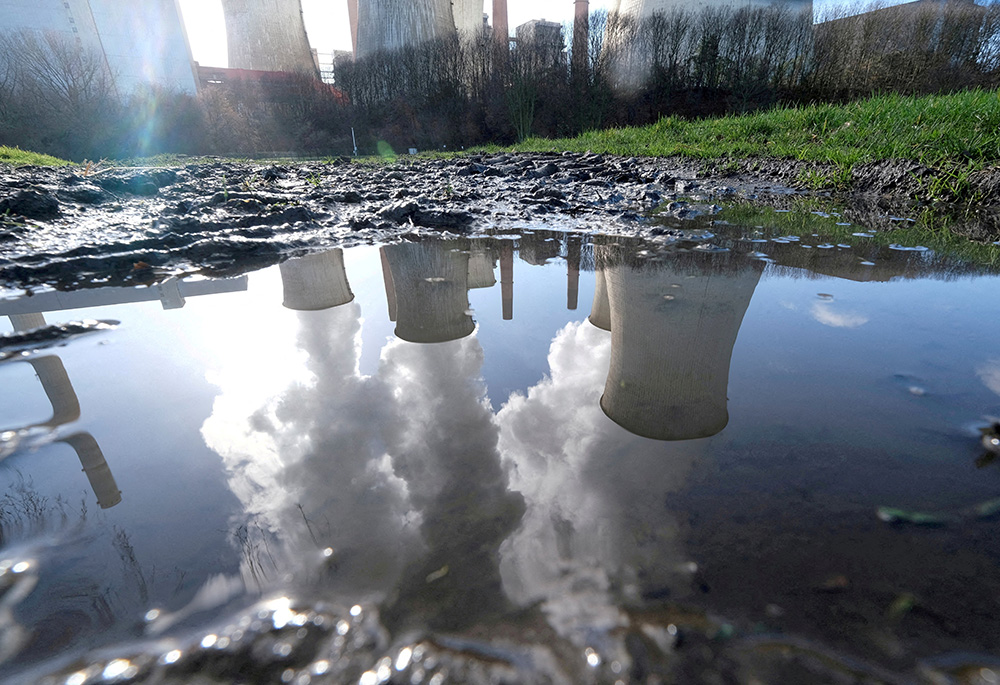 A coal power plant in Neurath, Germany, is seen reflected in a puddle of water Feb. 5, 2020. (CNS/Reuters/Wolfgang Rattay)