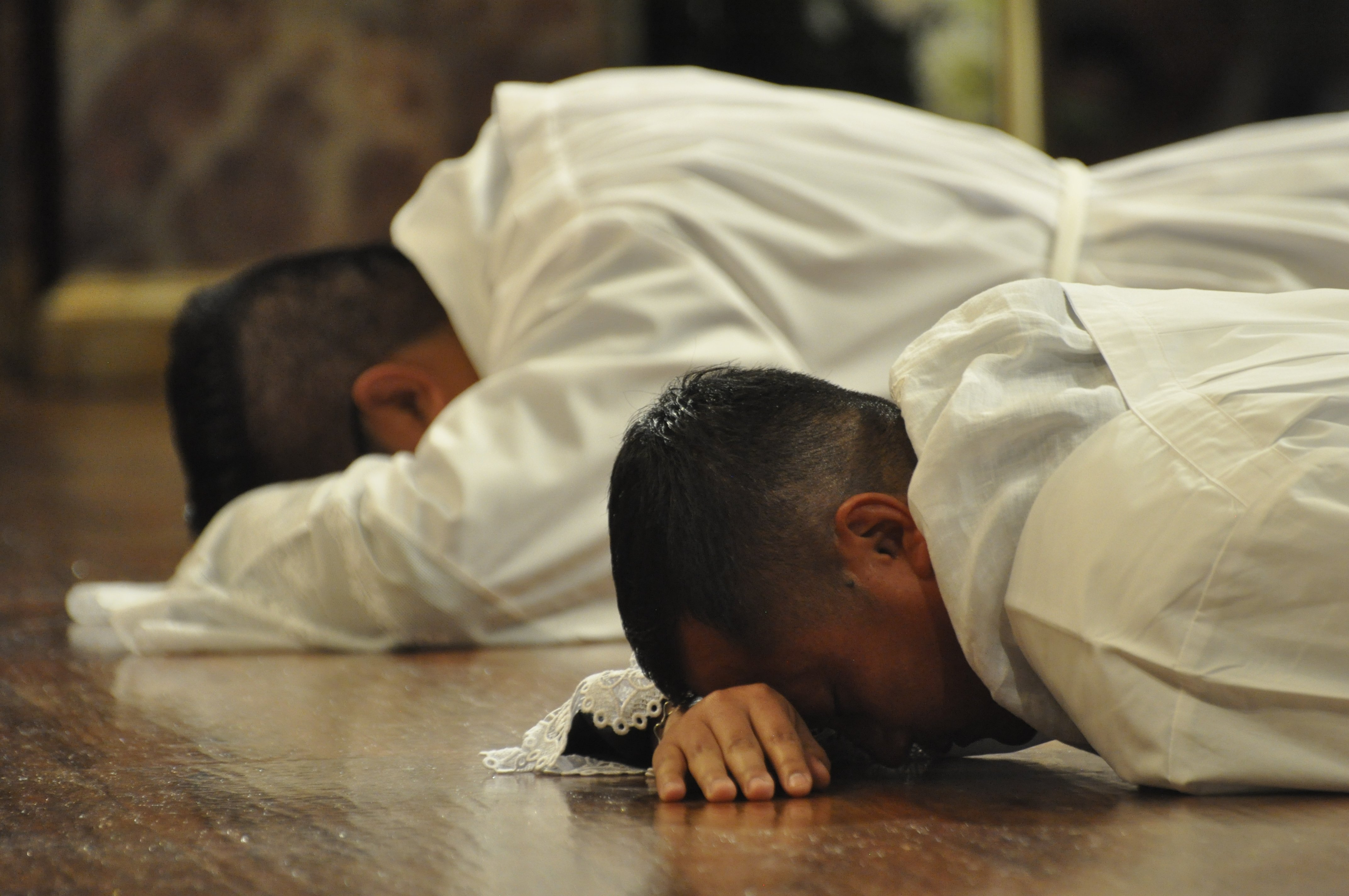 Seminarians Oscar Romero and Augustine Mang prostrate during the Litany of Supplication at their April 9 ordination as transitional deacons at Sagrado Corazon Church in Nashville's Catholic Pastoral Center. (CNS/Tennessee Register/Katie Peterson)