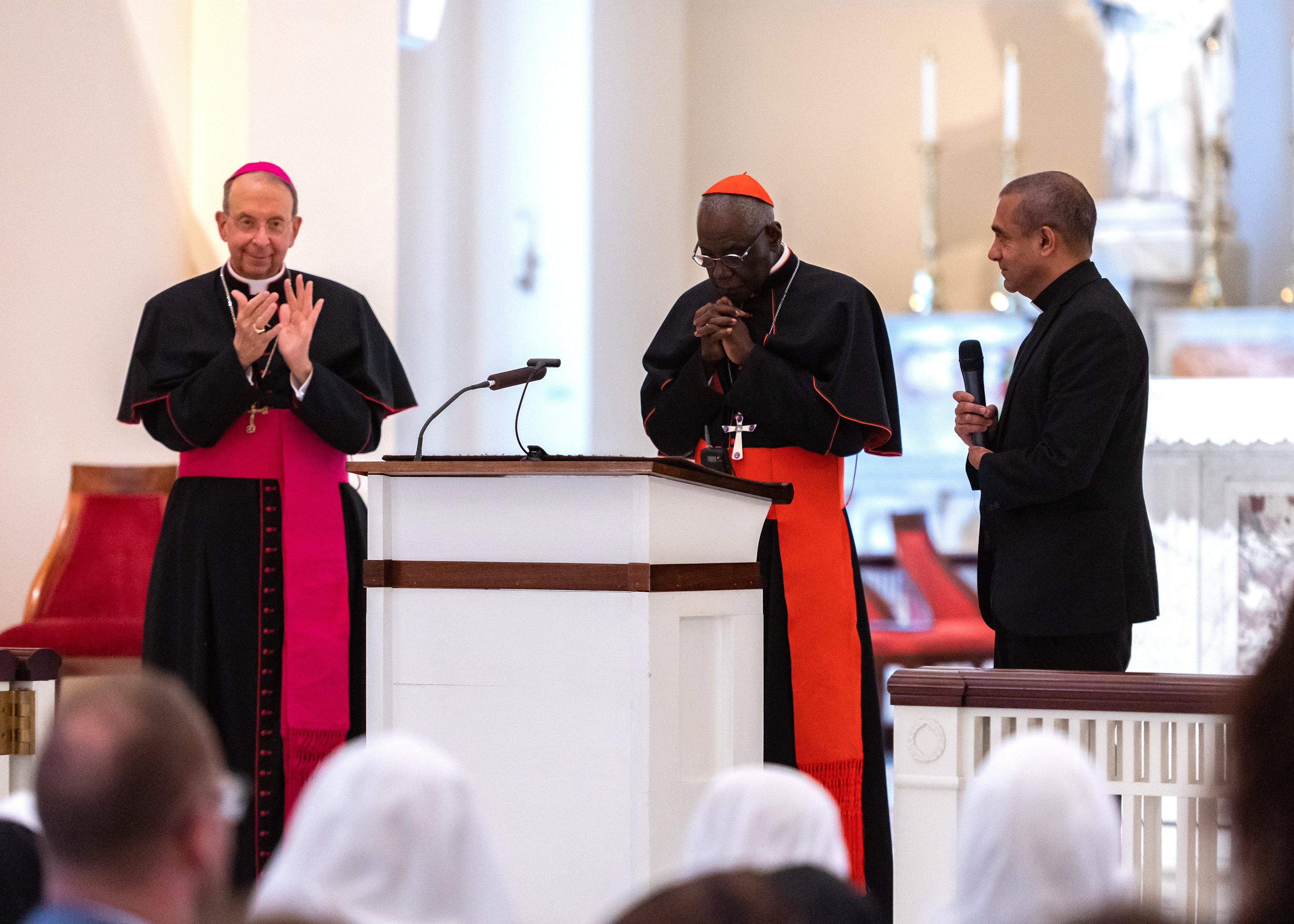 Baltimore Archbishop William E. Lori, left, leads a round of applause for Guinean Cardinal Robert Sarah May 15, 2022. (CNS photo/Kevin J. Parks, Catholic Review)