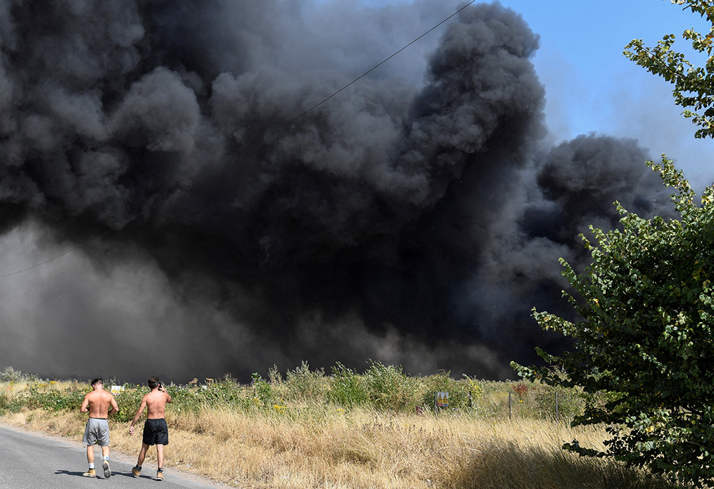 People watch as a fire burns during a heatwave July 19 in London. London's fire service had its busiest day since World War II dealing with several blazes in record-breaking temperatures, London Mayor Sadiq Khan said. (CNS/Reuters/Tony O'Brien)