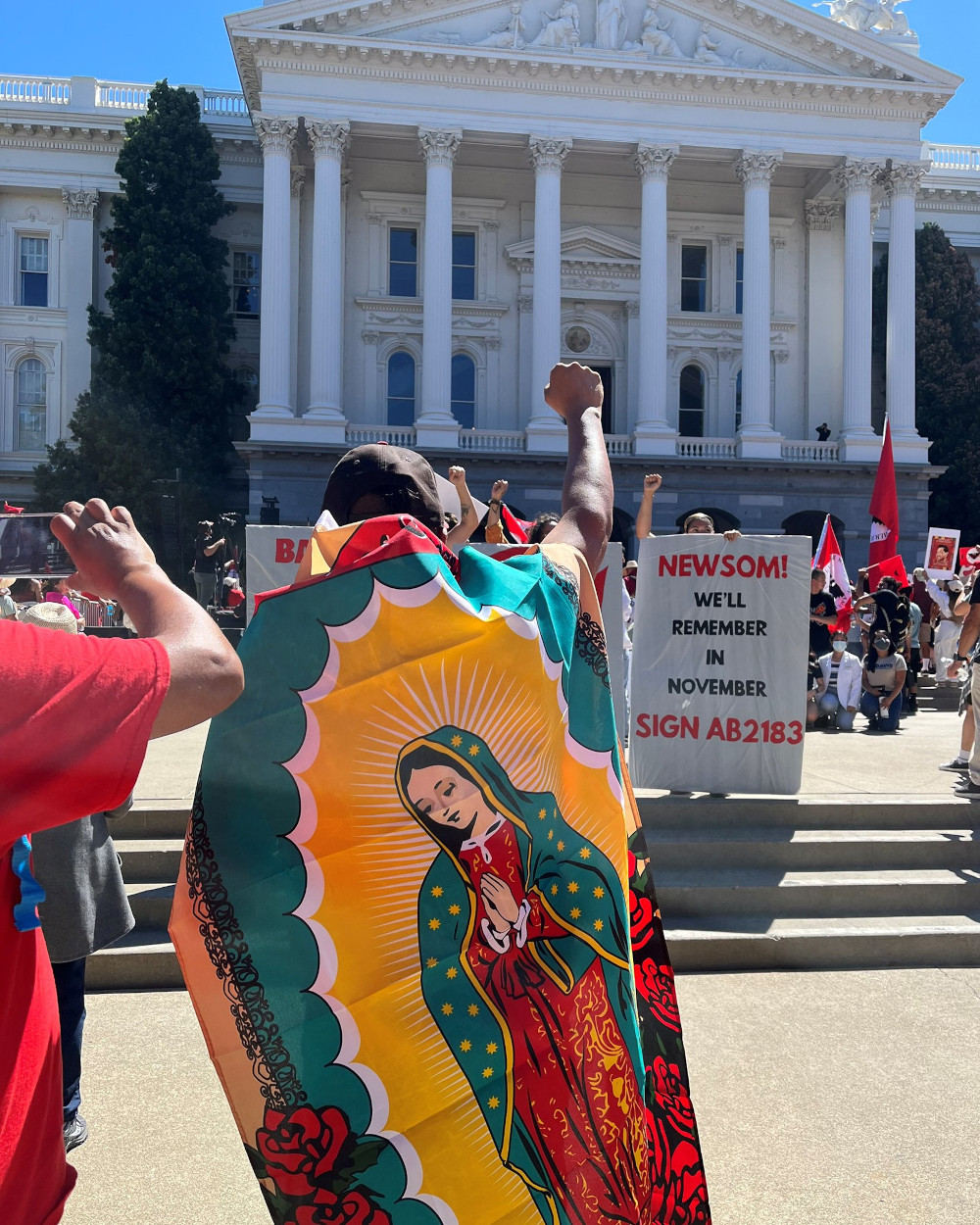 A marcher wearing an Our Lady of Guadelupe flag in Sacramento, Calif., stands in front of the state capitol building Aug. 26, 2022