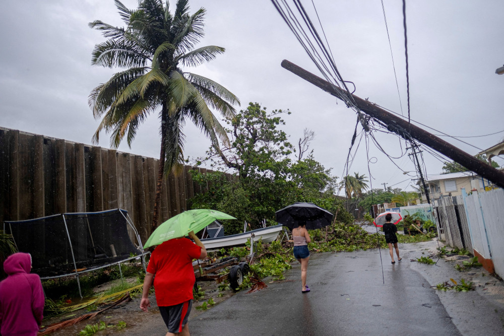 People walk on a street affected by the passing of Hurricane Fiona in Peñuelas, Puerto Rico, Sept. 19, 2022