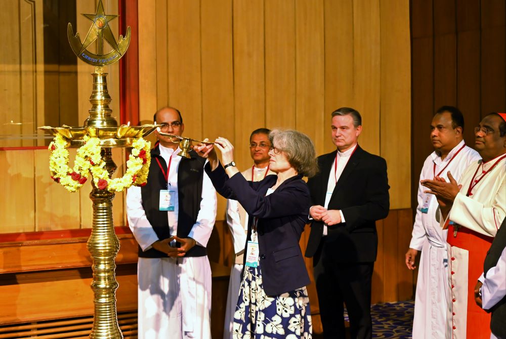 Woman lights candle while group looks on