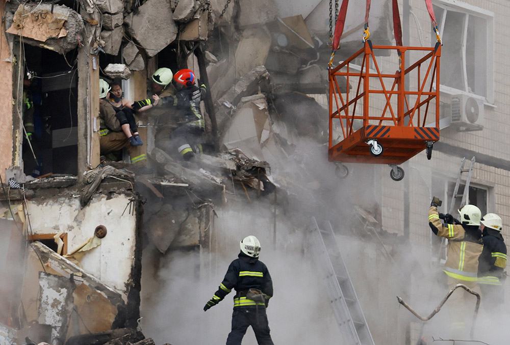 Emergency personnel evacuate a person Jan. 15 from a building in an apartment block that was heavily damaged by a Russian missile strike in Dnipro, Ukraine. (OSV News/Reuters/Clodagh Kilcoyne)