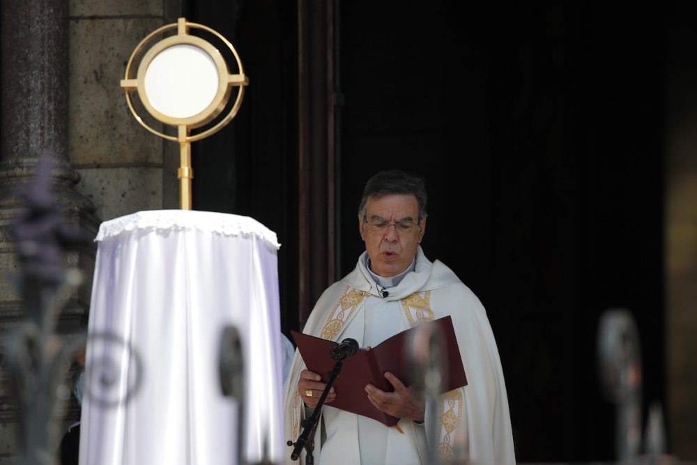 A white archbishop reads from a formal book inside a sanctuary