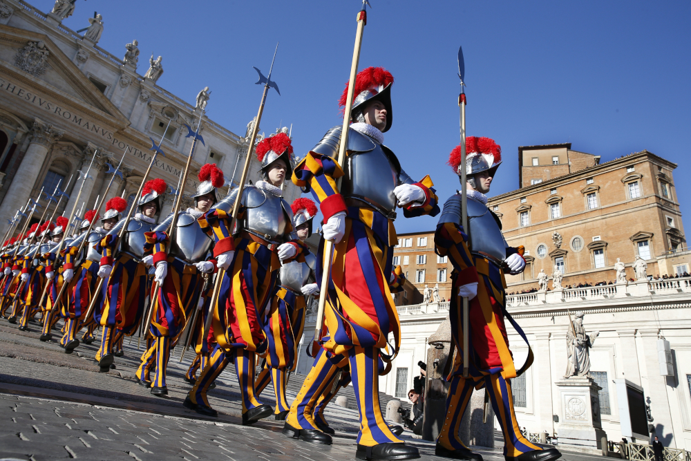 Two lines of men with striped pants and plumed helmets walk in lines