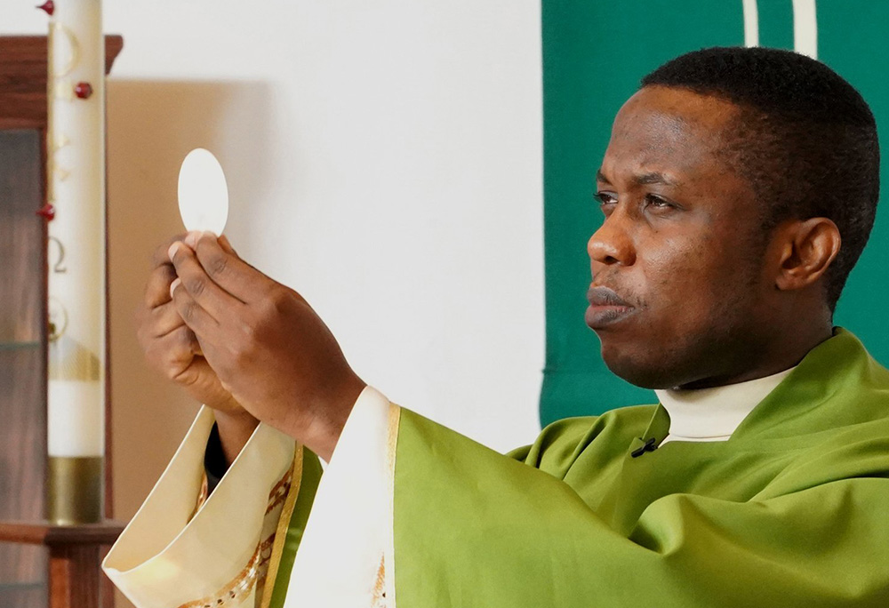 Fr. Patrick Ojiakor, a priest from the Diocese of Onitsha, Nigeria, raises the host during Mass Jan. 19, 2020, at a church in Central Islip, New York. (CNS/Gregory A. Shemitz)