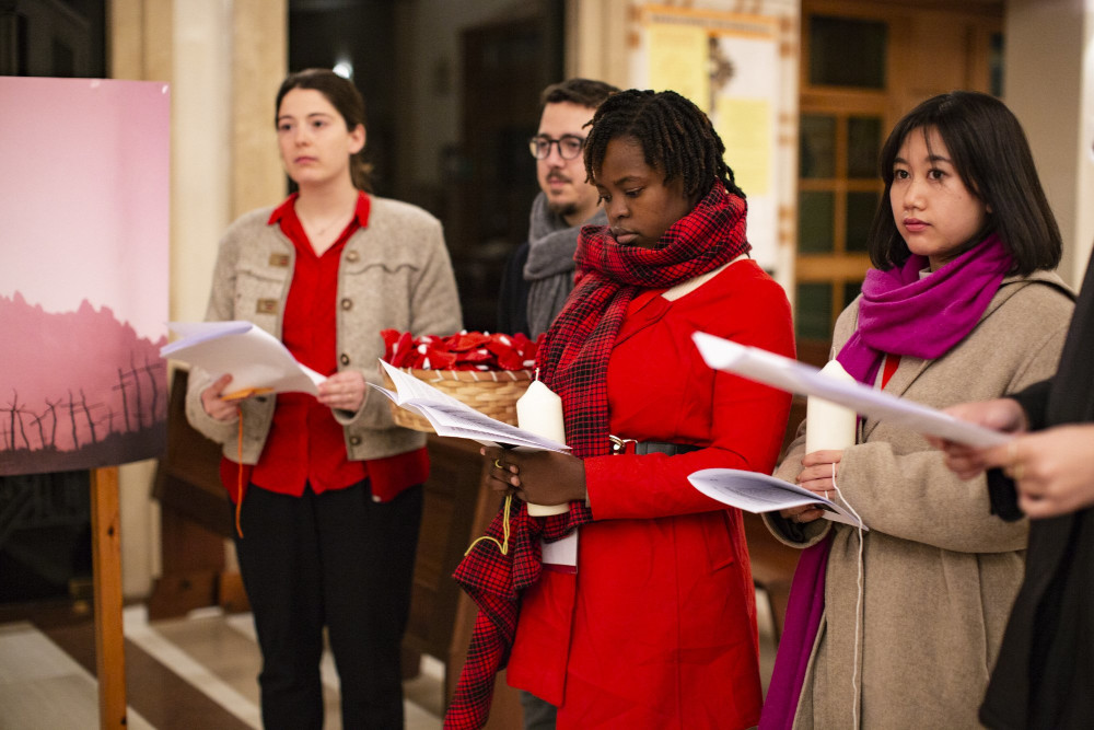 Four young people, two wearing red, hold sheets of paper