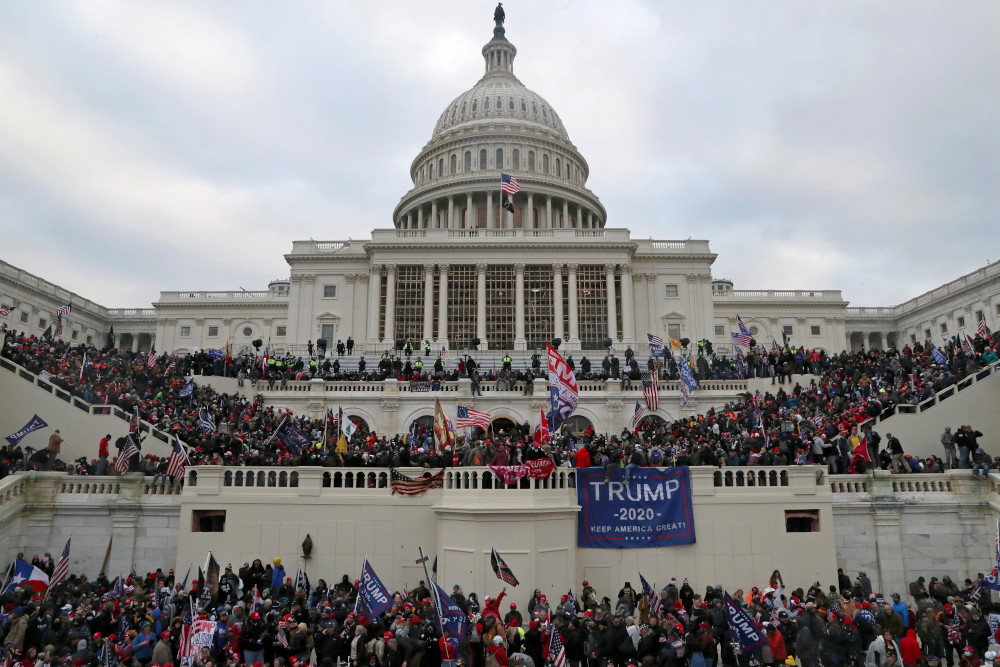 Crowds of people with Trump banners and American flags cover the outside of the Capitol building