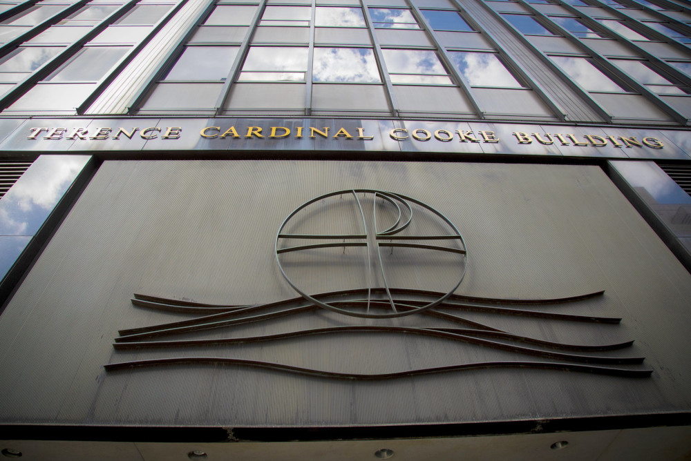 The front of a tall building with a cross and the words Terence Cardinal Cookie Building