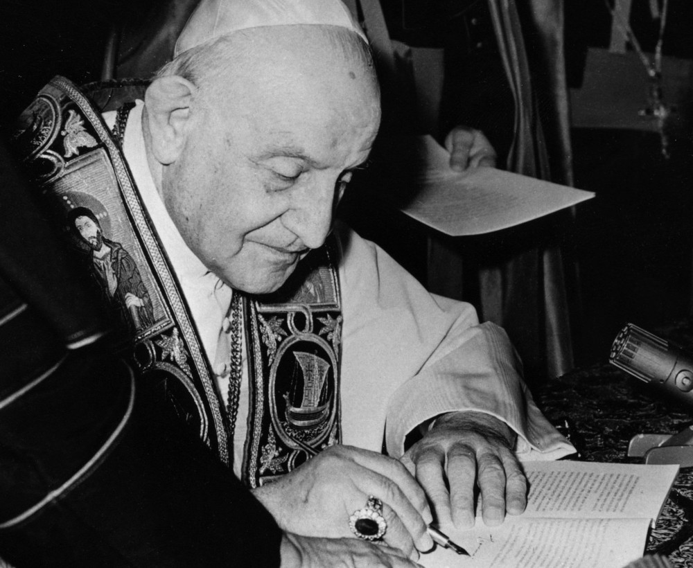 Black and white photo of a pope signing a document