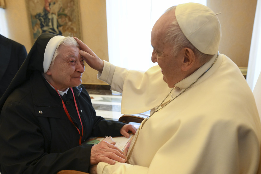 Pope Francis places his hand on a woman religious' forehead. 