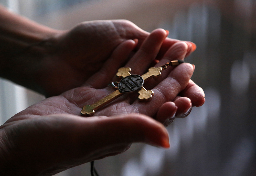 Christine Zuba holds the cross she wears when serving as a eucharistic minister at Sts. Peter and Paul Catholic Church at her home Feb. 14, 2022, in Blackwood, New Jersey. After coming out as transgender at age 58, Zuba, a lifelong Catholic, was welcomed into the parish. U.S. bishops issued a document dated March 20 rejecting gender-affirming medical treatments for transgender individuals and reasserting that such procedures must not be performed by Catholic providers. (AP photo/Jessie Wardarski)